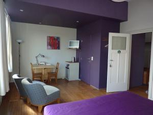 - une chambre avec des murs violets, une table et des chaises dans l'établissement W'allons nous dormir, à Liège