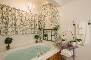 ein Bad mit einer Badewanne und ein Fenster mit Vorhängen in der Unterkunft Sutherland House Victorian Bed and Breakfast in Canandaigua