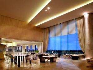 a restaurant with tables and chairs and a large window at Wyndham Grand Qingdao in Huangdao