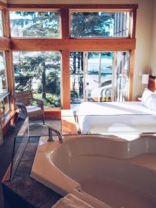 a bathroom with a tub and a bed and a bedroom at Pacific Sands Beach Resort in Tofino