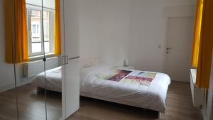 オーステンデにあるResidentie de Kaaiのベッドルーム1室(ベッド1台付)、黄色いカーテン付きの窓が備わります。