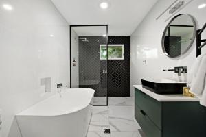 a white bathroom with a tub and a sink at Southern Belle Mollymook in Mollymook