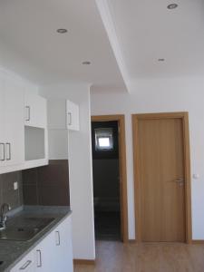 eine Küche mit weißen Schränken und einer Holztür in der Unterkunft Appartement Belvédère Estrela in Lissabon