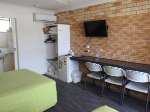a room with a tv and a chair at Urangan Motor Inn in Hervey Bay