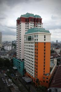 a tall building with an orange and white at Horison Arcadia Mangga Dua in Jakarta