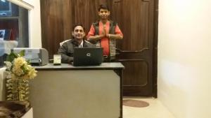two men standing at a desk with a laptop at Hotel Vacation in Jaipur