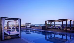 a pool with chairs and a pavilion on top of a building at Pullman Dubai Creek City Centre in Dubai