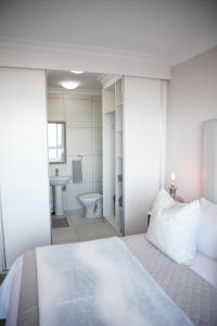 a bedroom with a bed and a bathroom with a toilet at view at the bay 4 in Mossel Bay