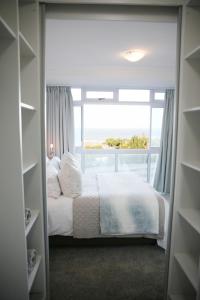 a bedroom with a bed and a large window at view at the bay 4 in Mossel Bay