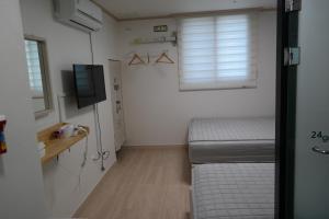 een kleine kamer met 2 bedden en een televisie bij 24 Guesthouse Suncheon in Suncheon