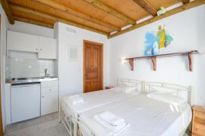 a white bedroom with a bed and a kitchen at Mike's Studios in Naxos Chora