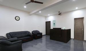 uma sala de espera com mobiliário de couro preto e um relógio em Treebo Trend Hi Line Apartments Kalapatti em Coimbatore