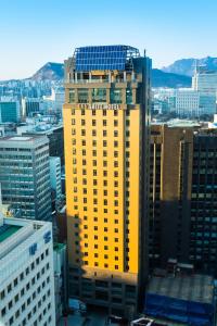 a yellow building with a sign on it in a city at ENA Suite Hotel Namdaemun in Seoul