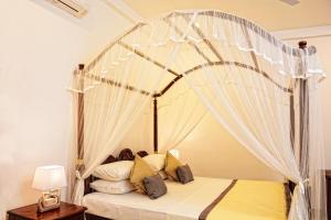 Horizon Villa في يوناواتونا: غرفة نوم بسرير مظلة مع ستائر بيضاء