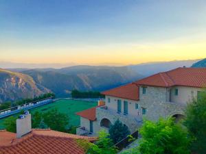 a view of a house with a green field in the mountains at Aegli Arachova in Arachova