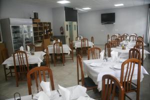 a dining room with tables and chairs with white tablecloths at Hostal El Altet in El Alted