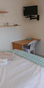 a bedroom with a bed with a desk and a television at Humewood Home Stay in Port Elizabeth