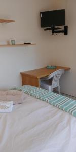 Un dormitorio con una cama con un escritorio y un televisor. en Humewood Home Stay, en Port Elizabeth