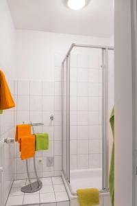 ein Bad mit einer Dusche sowie orangefarbenen und grünen Handtüchern in der Unterkunft Apartment Wideystrasse in Witten