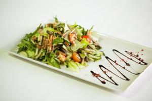 un plato blanco con una ensalada en una mesa blanca en Kupecheskiy Club Hotel, en Bor