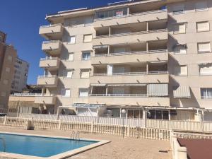 un immeuble d'appartements avec une piscine en face dans l'établissement Apartamentos Arenales del Sol, à Arenales del Sol