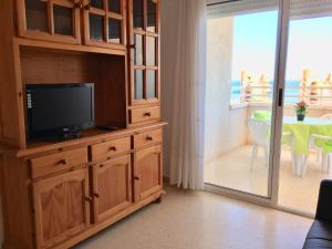 a living room with a tv on a wooden cabinet at Apartamentos Arenales del Sol in Arenales del Sol