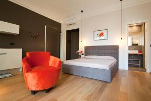 a bedroom with a bed and a red chair at Luxury Flat Riberi sotto la Mole in Turin