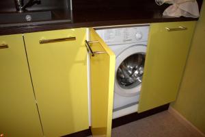 カザンにあるWasabi Apartmentのキッチン(洗濯機、乾燥機、黄色のキャビネット付)
