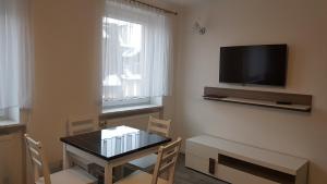 a dining room with a table and a television on the wall at Apartament Centrum 1 in Mikołajki
