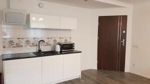 a white kitchen with a sink and a microwave at Apartament Centrum 1 in Mikołajki