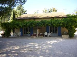 Casa pequeña con porche con sillas y árboles en Les Cigales, en Saint-Andiol