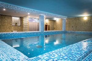 a large swimming pool with blue tiles in a bathroom at Aivengo Hotel in Rivne