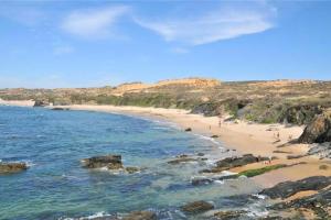 a beach with people walking on the sand and the water at Casa do Almograve in Almograve