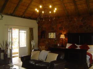 a living room with a leather couch and a chandelier at Forest Creek Lodge & Spa in Badfontein