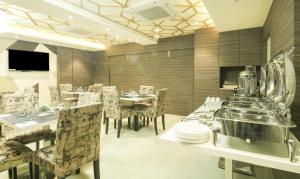 加尔各答Treebo Hoops, Near Kolkata Airport的一间配有桌椅和电视的餐厅