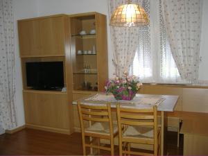 a dining room table with chairs and a vase of flowers at Residence Hotel Montechiara in Baselga di Pinè