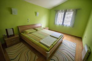 a green bedroom with a bed and a window at Apartments Ćuković in Risan