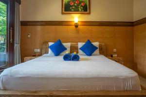 een slaapkamer met een groot wit bed met blauwe kussens bij Three Brothers Guest House in Ubud