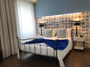 a white bed with a blue comforter on top of it at Welcome In in Aveiro