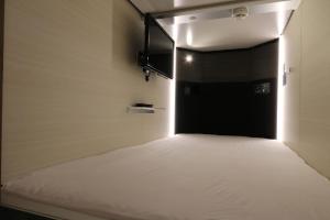 a room with a bed with a black door at Cabin & Capsule Hotel J-SHIP Osaka Namba in Osaka