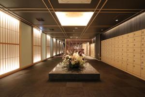 a hallway with a table with flowers in it at Cabin & Capsule Hotel J-SHIP Osaka Namba in Osaka