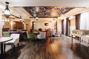 a restaurant with tables and chairs and a ceiling at Renion Park Hotel in Almaty
