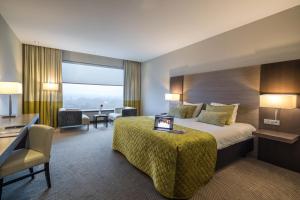 una camera d'albergo con un grande letto e una scrivania di Van der Valk Airporthotel Düsseldorf a Dusseldorf