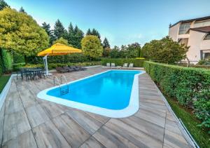 een zwembad in een achtertuin met een tafel en een parasol bij Cardano Hotel Malpensa in Cardano al Campo