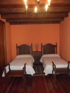 2 Betten in einem Zimmer mit orangefarbenen Wänden in der Unterkunft La Canaleja in Cigüenza