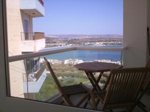 een balkon met een houten tafel en 2 stoelen bij Garden View Apartment in Mellieħa