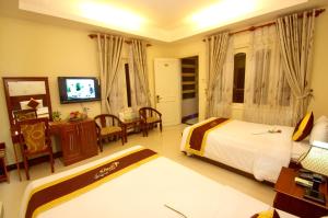 a hotel room with two beds and a television at Luxury Nha Trang Hotel in Nha Trang