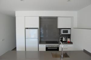 cocina con armarios blancos y nevera de acero inoxidable en Apartament Cortey en Calella de Palafrugell