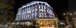 un edificio iluminado con gente parada frente a él en Hotel Colosseo Tirana en Tirana