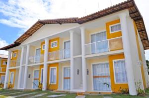 un gran edificio blanco y amarillo con ventanas en apartamento monte hebron, en Porto Seguro